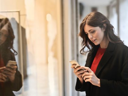 Young woman holding smartphone in front of a shop