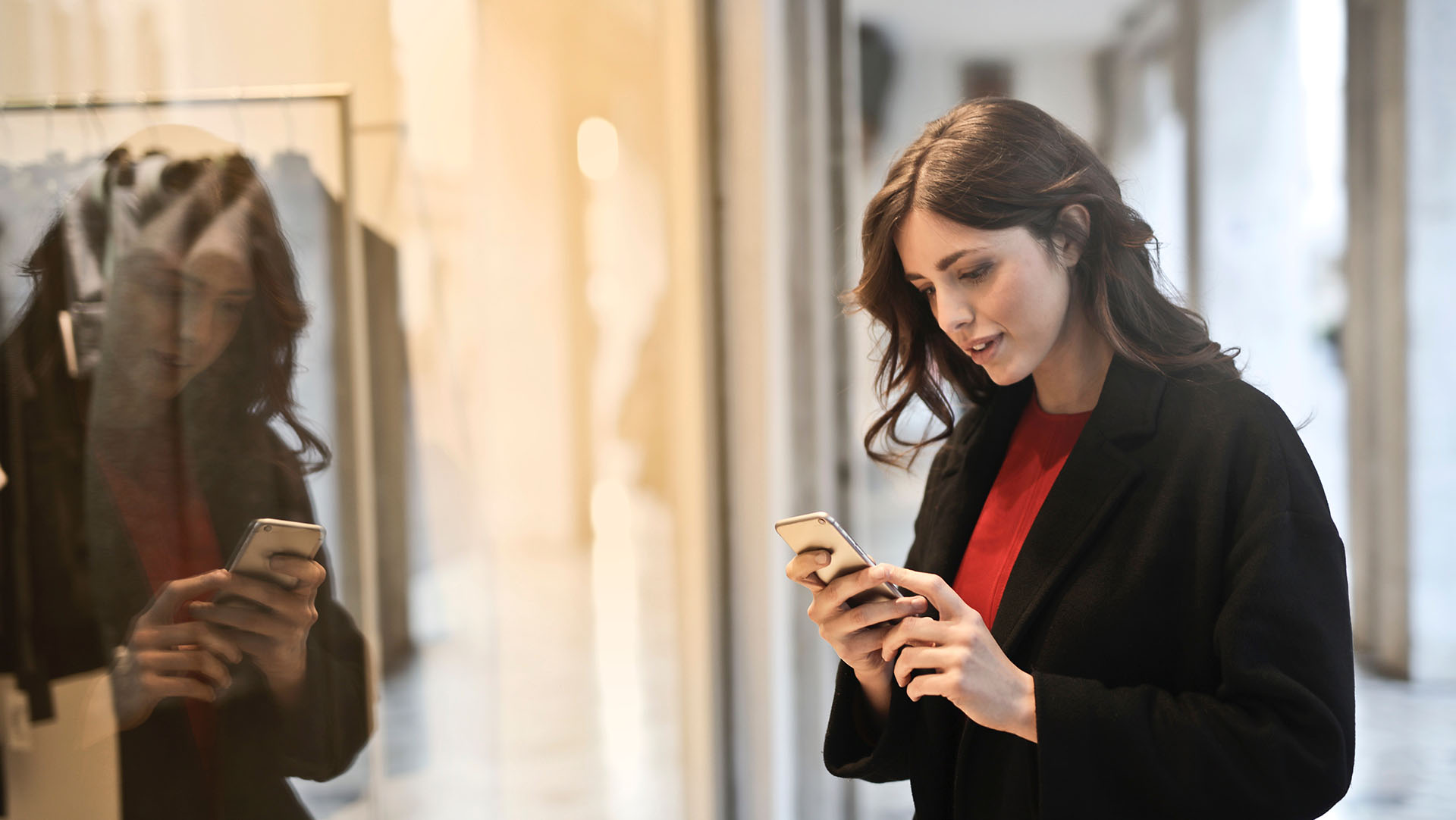 Young woman holding smartphone in front of a shop